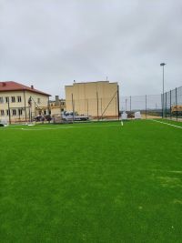 Boisko do piłki nożnej w trakcie budowy, w tle budynek Zespołu Szkół w Sadkowicach